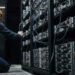 Engineer adjusting Bitcoin mining servers in a data center amid network power struggle over anti-spam proposal and disputed node support