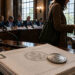 Congressional hearing room with U.S. documents and a dollar coin in the foreground as a woman pays by phone, symbolizing stablecoins becoming easier to use while Bitcoin still awaits regulatory clarity